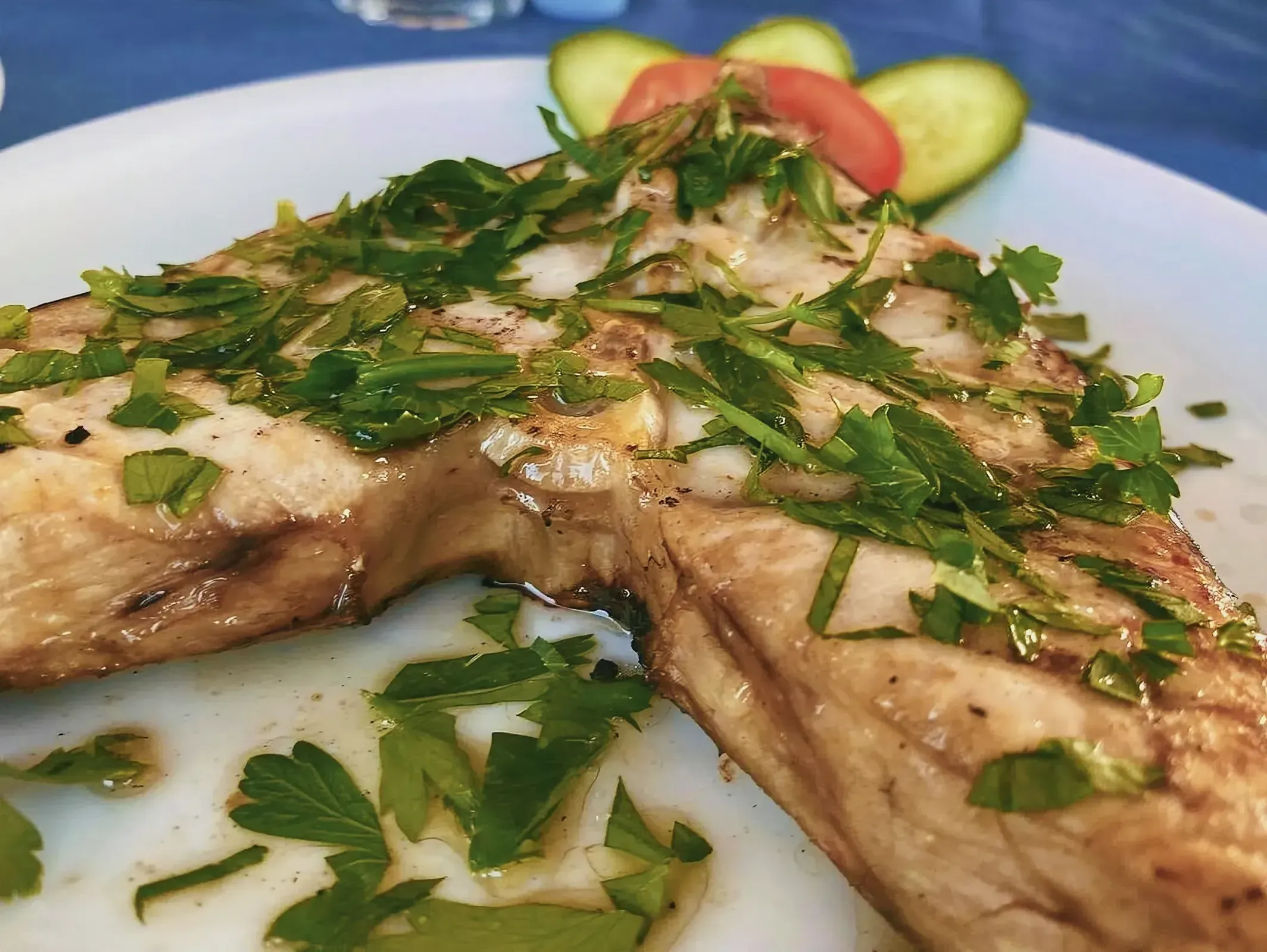 Beautifully garnished piece of fish on a plate with fresh herbs