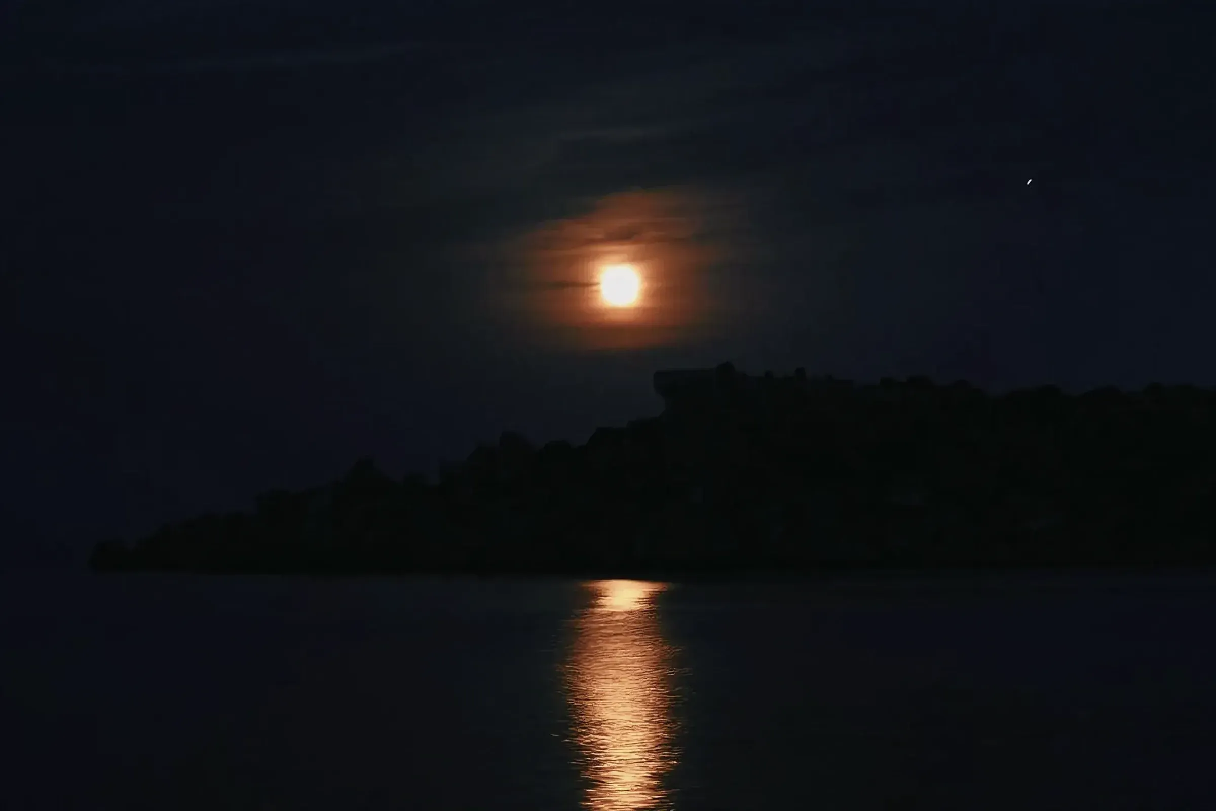 Tranquil nocturnal landscape with full moon reflections on a lake