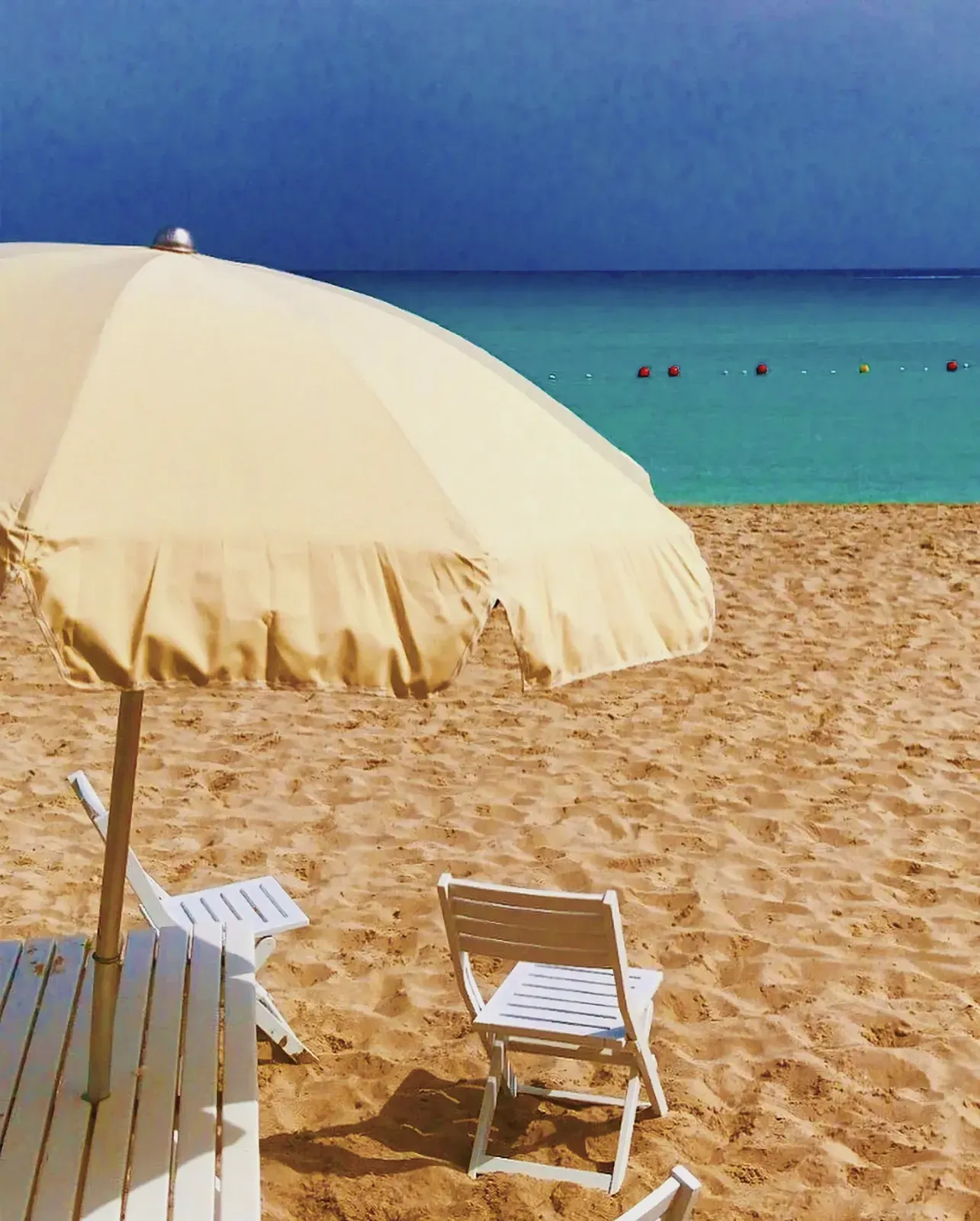 A serene beach with a white chair and umbrella.