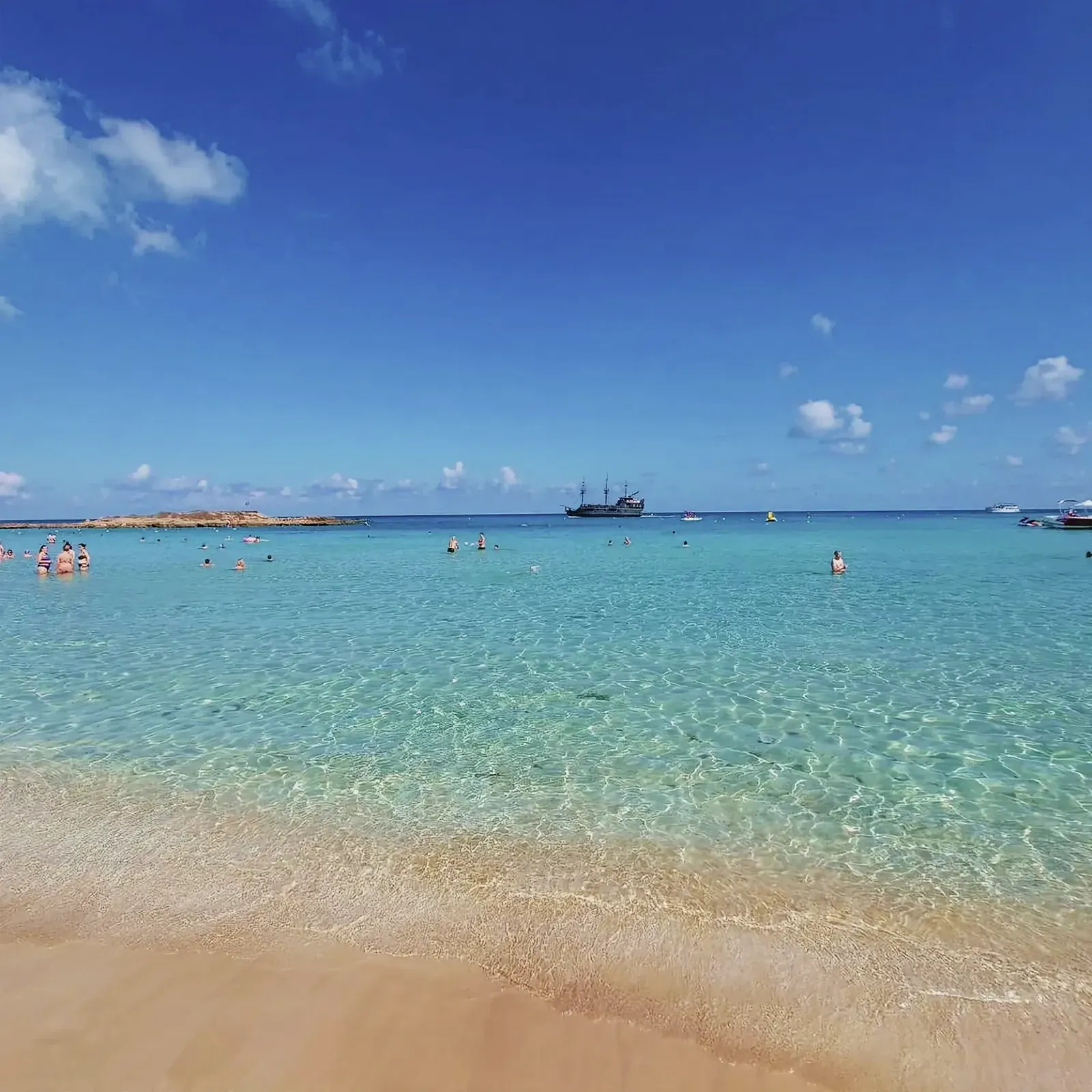 People enjoying the golden beaches and clear waters of Fig Tree Bay in Protaras, Cyprus.