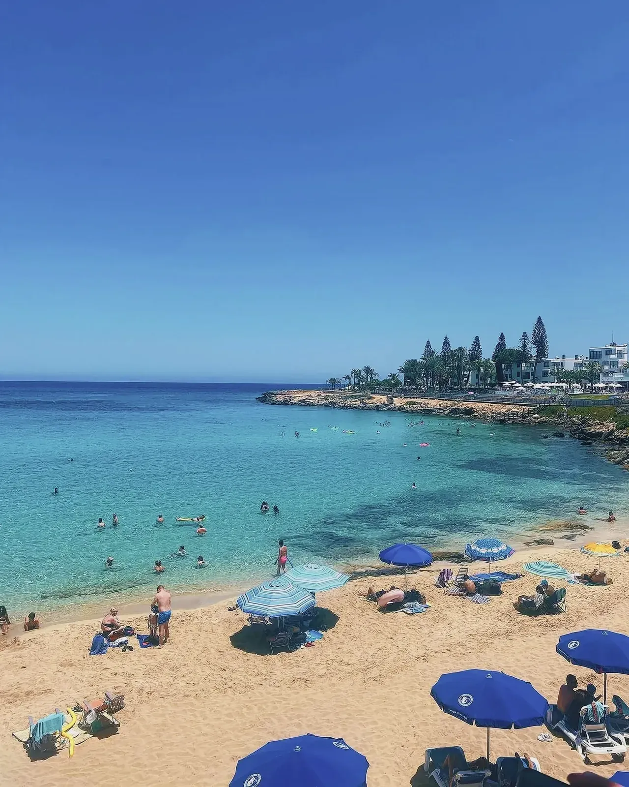 Fig Tree Bay beach with clear blue water and people enjoying the sun.